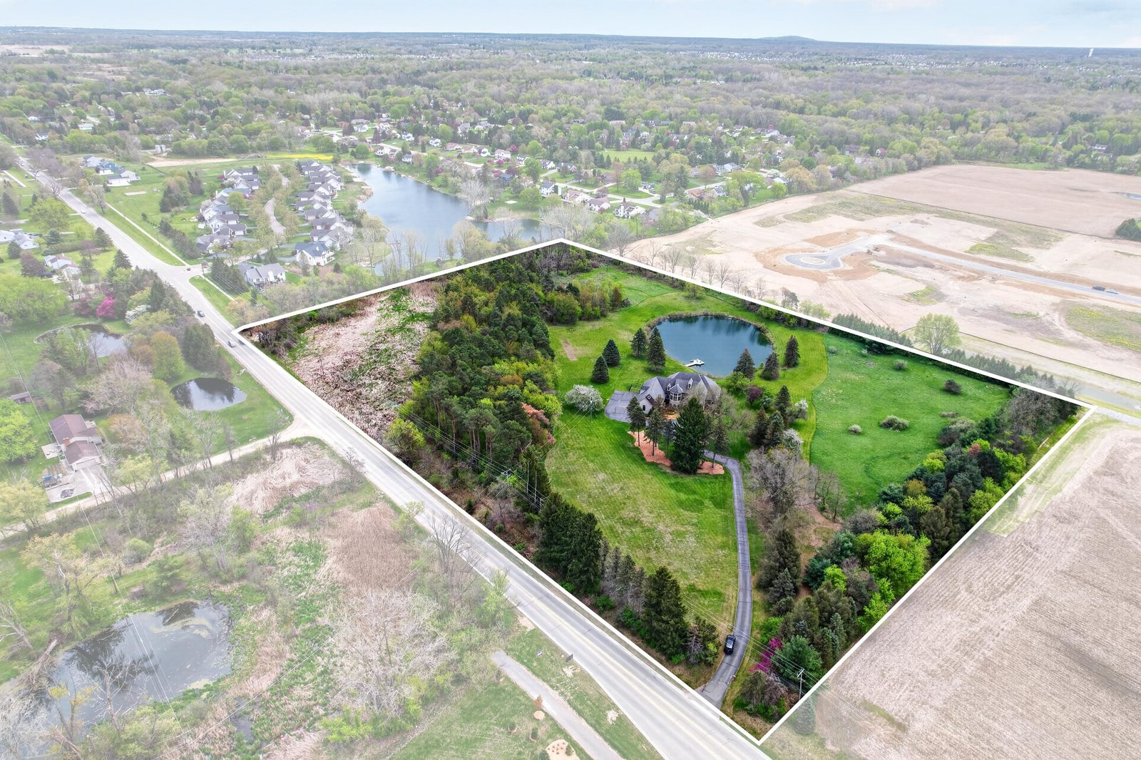 Aerial view of 60675 Pontiac Trail showing the 12.87-acre property boundary, pond, and surrounding grounds in New Hudson, Michigan