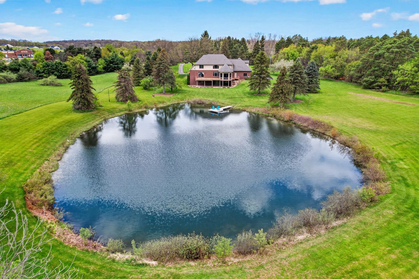 Aerial view of the spring-fed pond and dock with surrounding grounds at 60675 Pontiac Trail