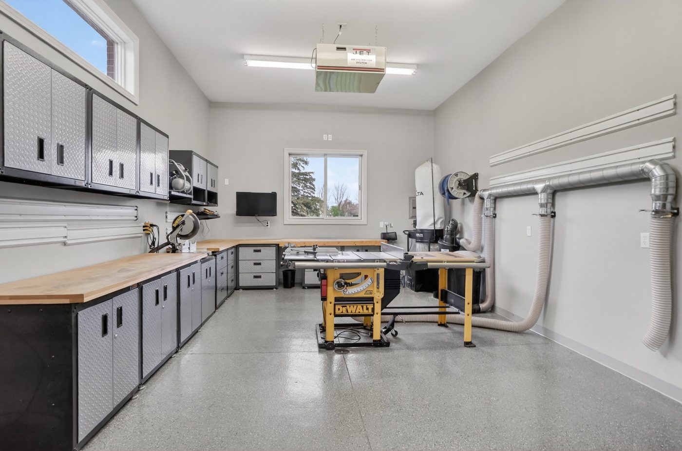 Professional workshop with radiant heated floors, dust collection, table saw, and cabinetry at 60675 Pontiac Trail