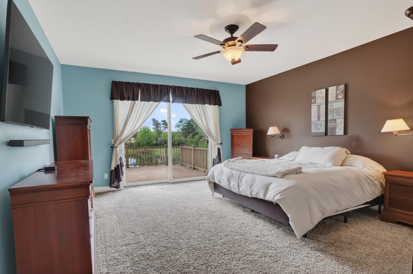 Main-floor primary bedroom with sliding doors opening to the deck and pond views at 60675 Pontiac Trail